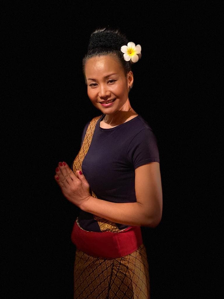 Yom in traditionele Thaise kleding begroet met gevouwen handen.
