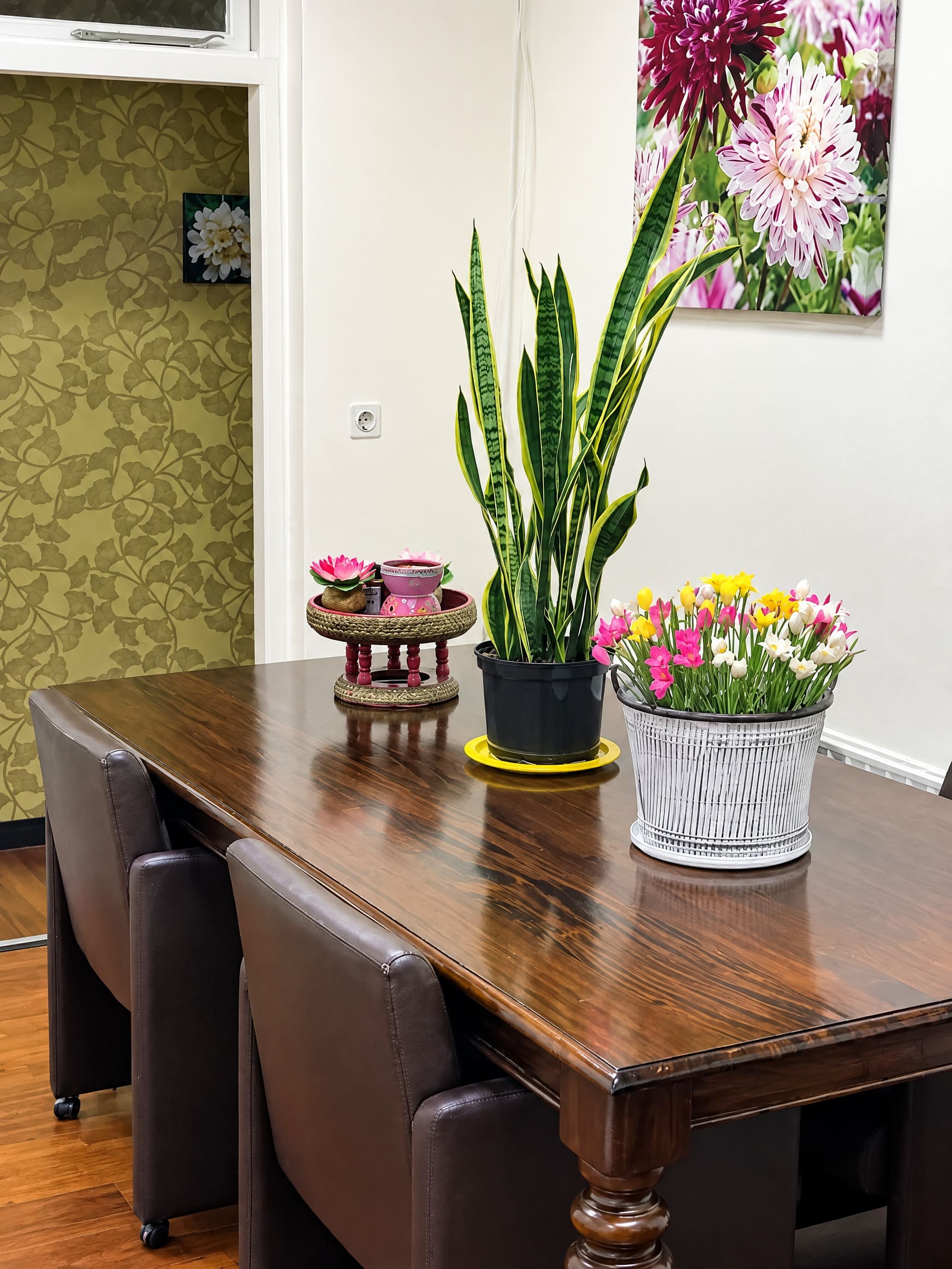 De ontvangstruimte met een houten tafel, bloemen en een schaaltje met lotusbloemen.