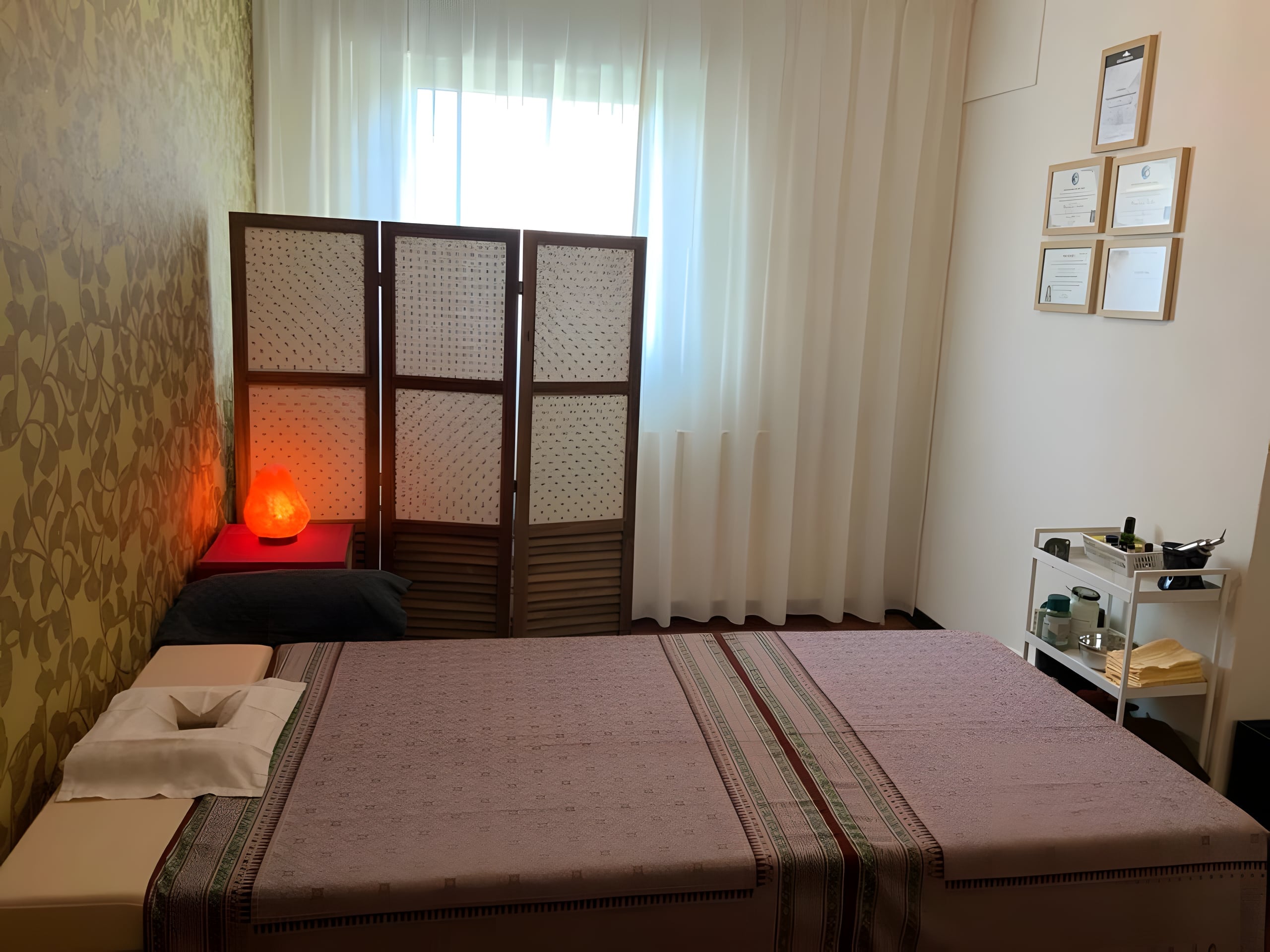 Behandelkamer van I-Saan Massage met massagebed, kamerscherm en een gloeiende zoutlamp.